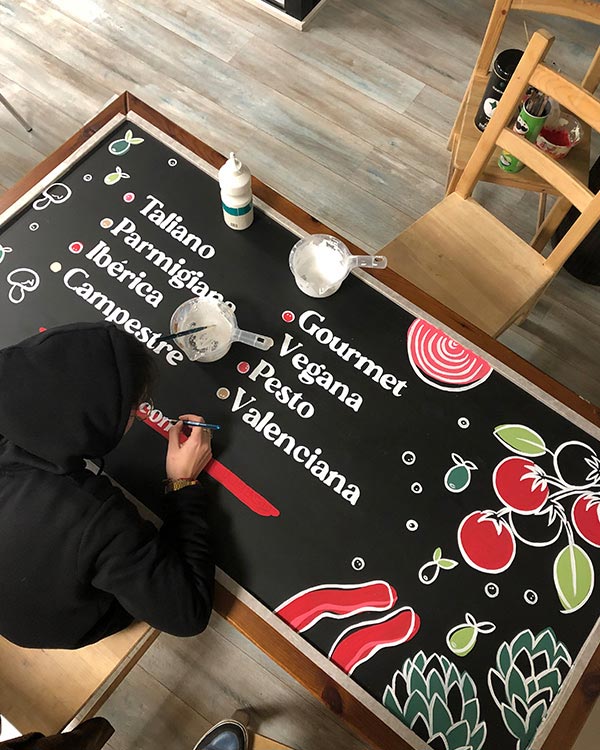 proceso de la pizzarra pintada con pincel con diseño personalizado para branding y decoracion de local comercial